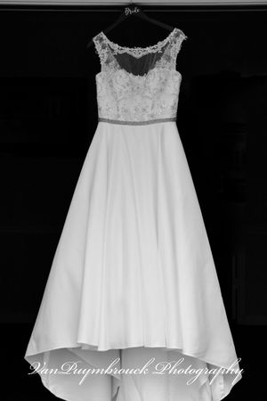 A series of white wedding dresses with lace details displayed against a black background.
