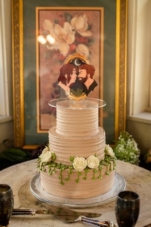 Simple white tiered wedding cake decorated with roses and greenery on elegant display table.