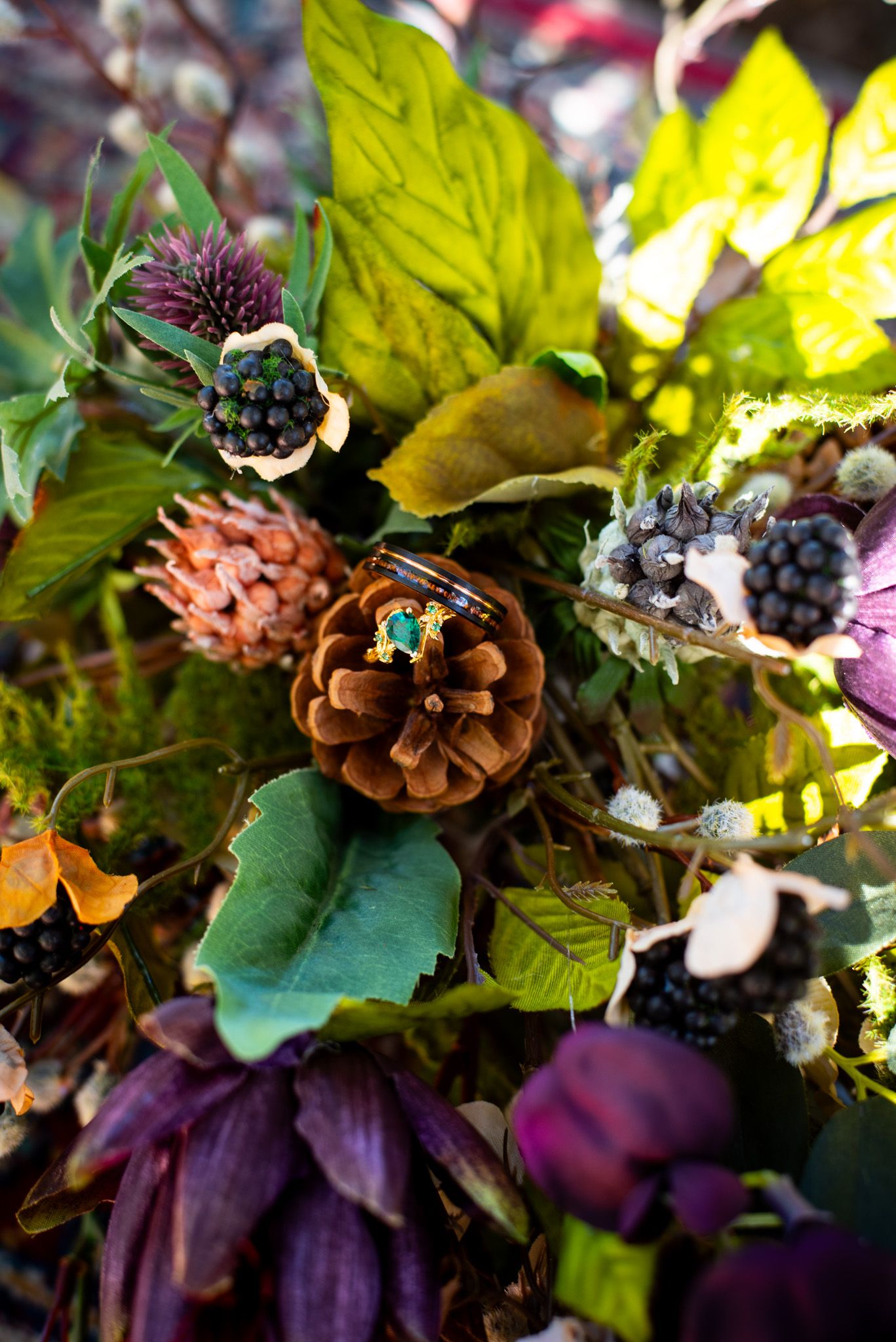 Artistic detail shot of autumn wedding bouquet with pinecones, purple flowers and fall foliage.