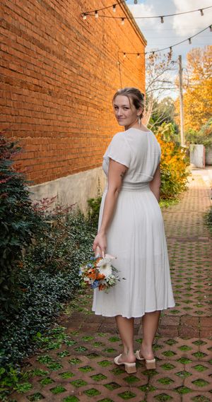 A series of photos showing someone in a white dress against a brick wall with string lights and autumn foliage.