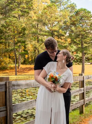 A couple shares an intimate moment by a pond with lily pads during an autumn wedding photoshoot.
