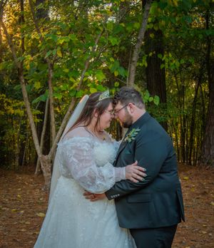 Romantic wedding couple shares intimate moment in a wooded setting during golden hour.