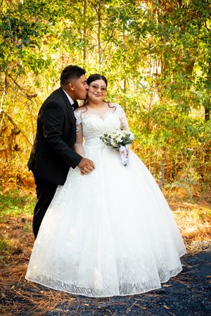 An intimate wedding portrait showing a stunning white ball gown against a backdrop of sunlit autumn trees.