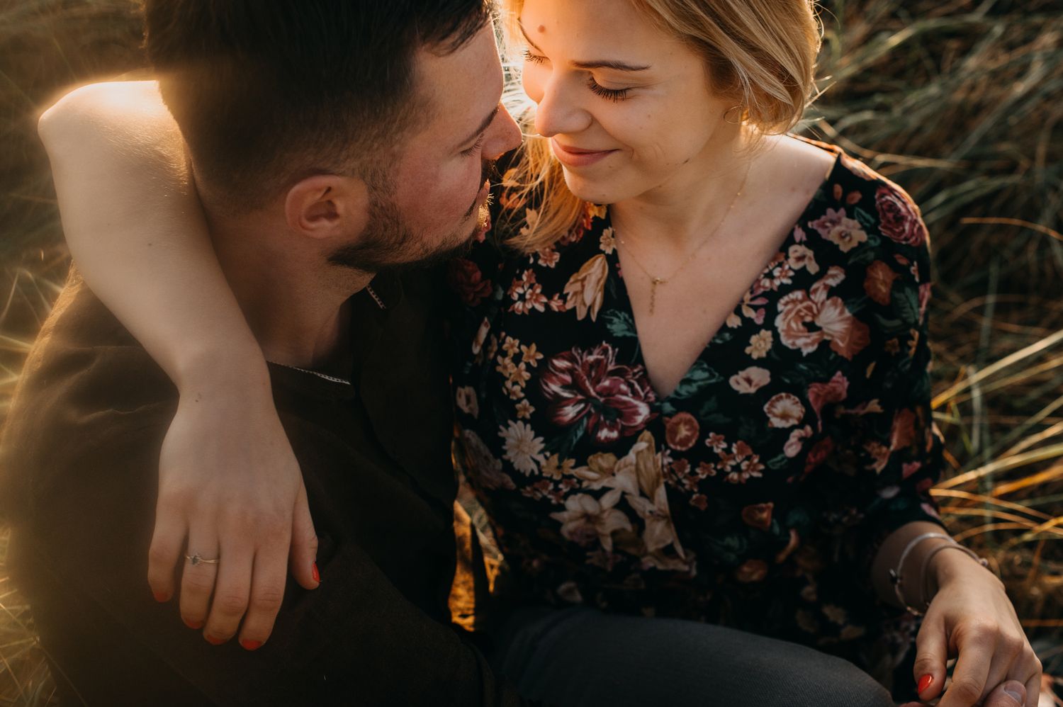 A romantic couple shares an intimate moment in golden sunlight while sitting together outdoors.