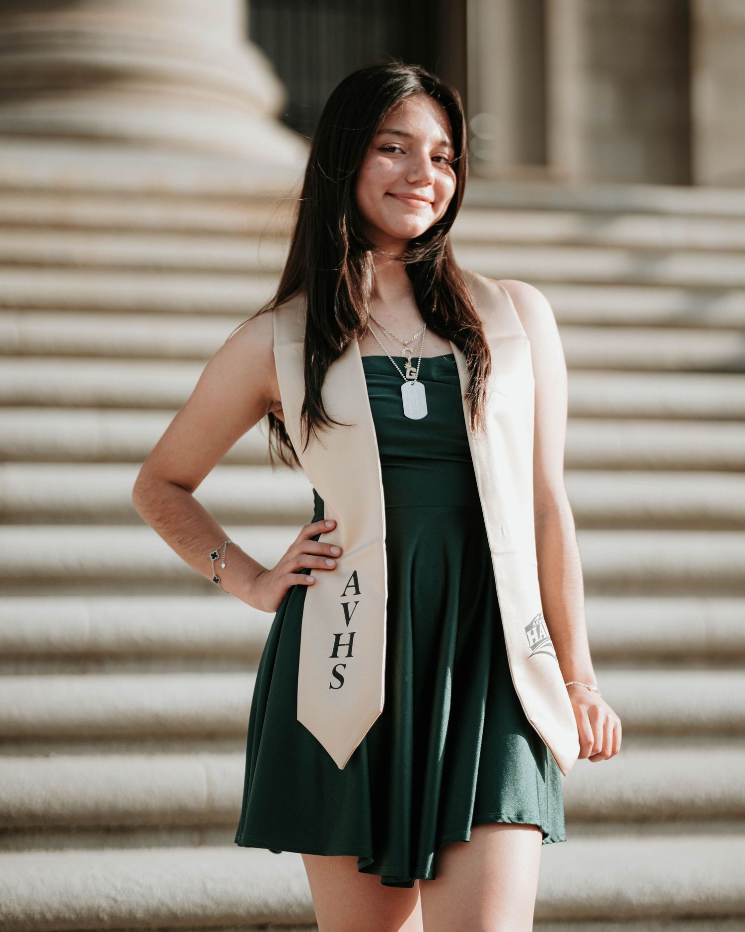 Graduation photos showing a white blazer over dark dress on stone steps with classic architectural backdrop.