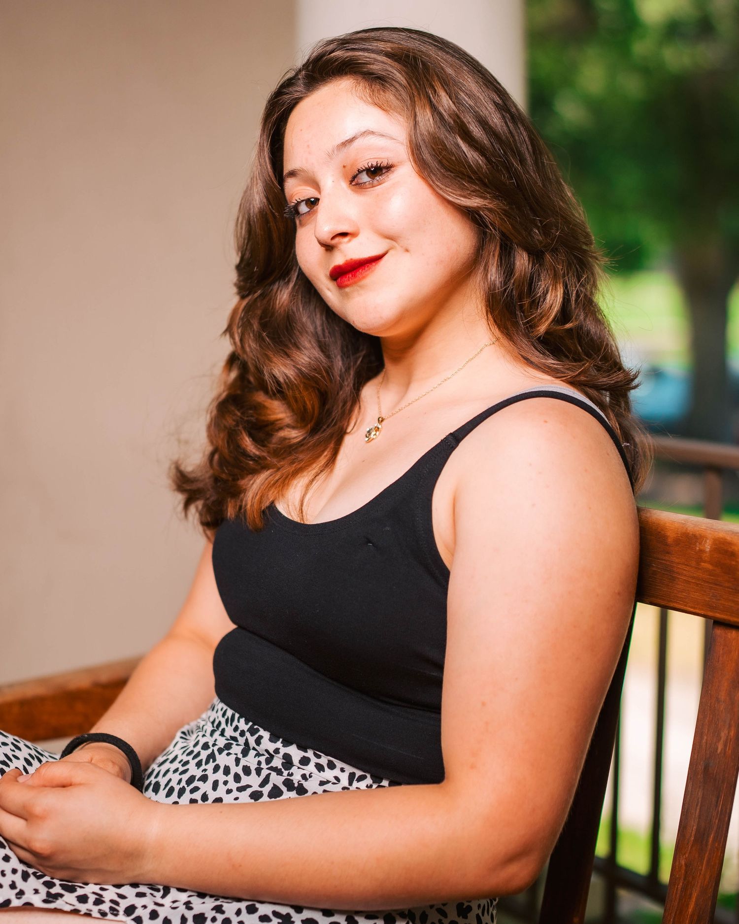 A woman in a black top and animal print dress poses outdoors in a series of casual portrait shots.