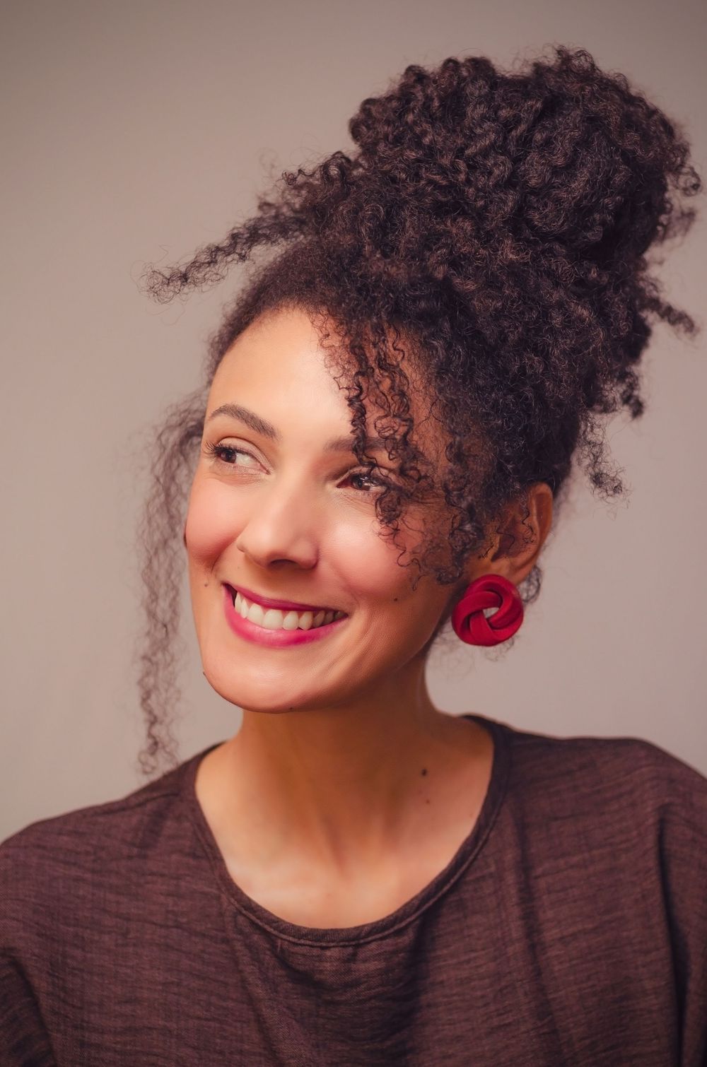 Retrato feminino em estúdio na Tijuca, RJ. Mulher sorrindo com cabelo cacheado preso. Exemplo de foto de perfil profissional e pessoal.