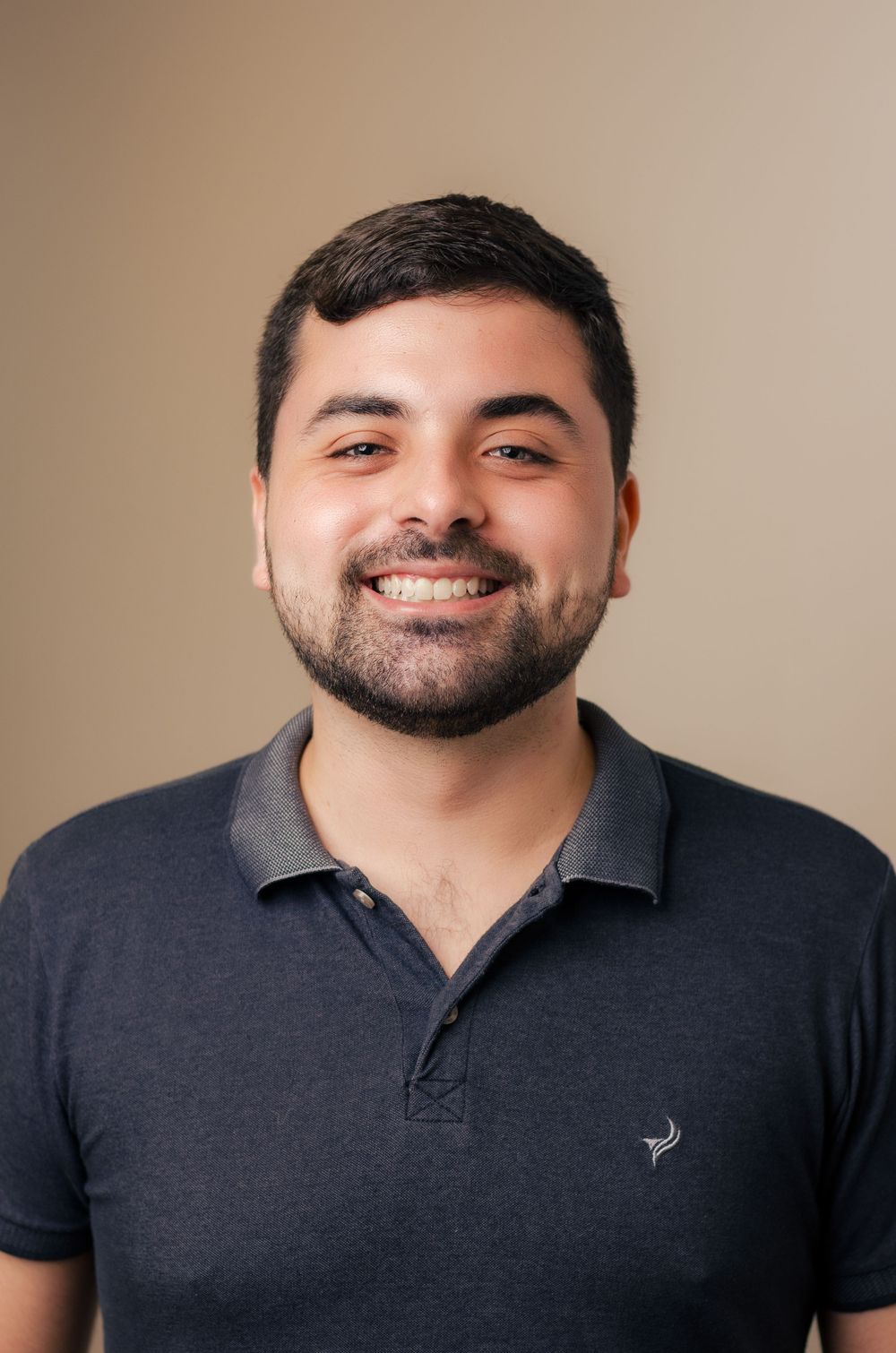 Retrato corporativo moderno de homem sorrindo com camisa polo escura. Exemplo de fotografia profissional (headshot).