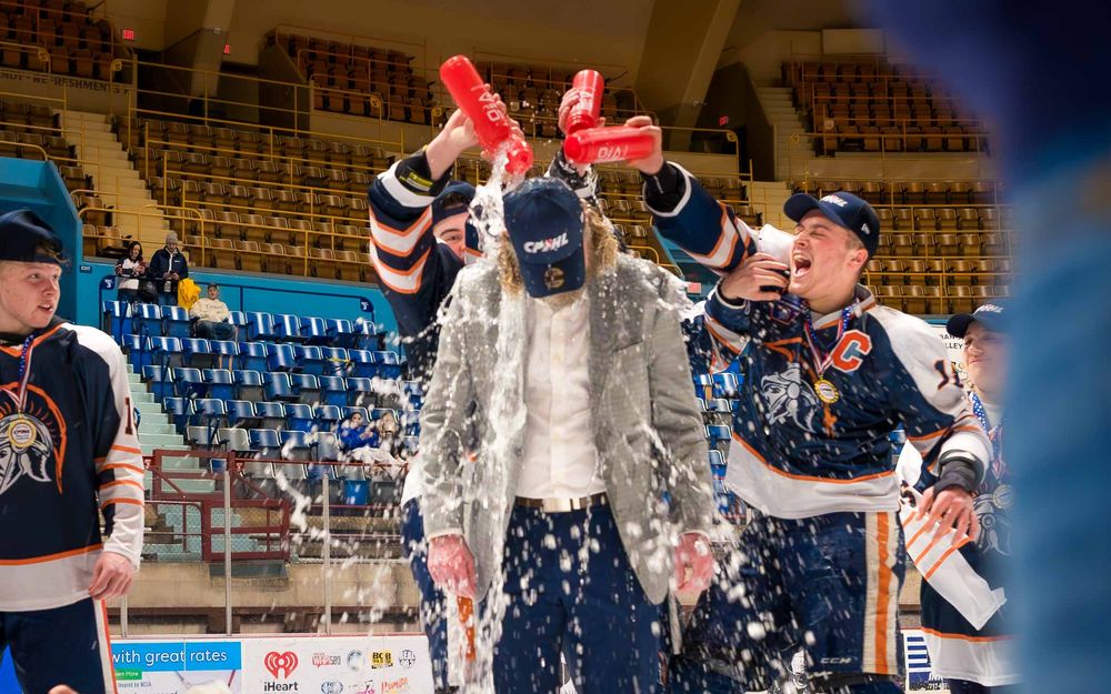 Trojans hockey coach gets drenched in a celebratory water bottle shower after the championship win by SportsFox Photography, Hershey PA.