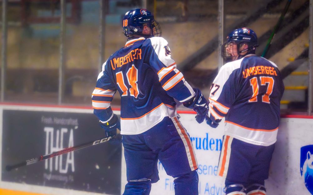 Trojans players celebrate after a goal—one congratulates the scorer for the assist by SportsFox Photography, Hershey PA.