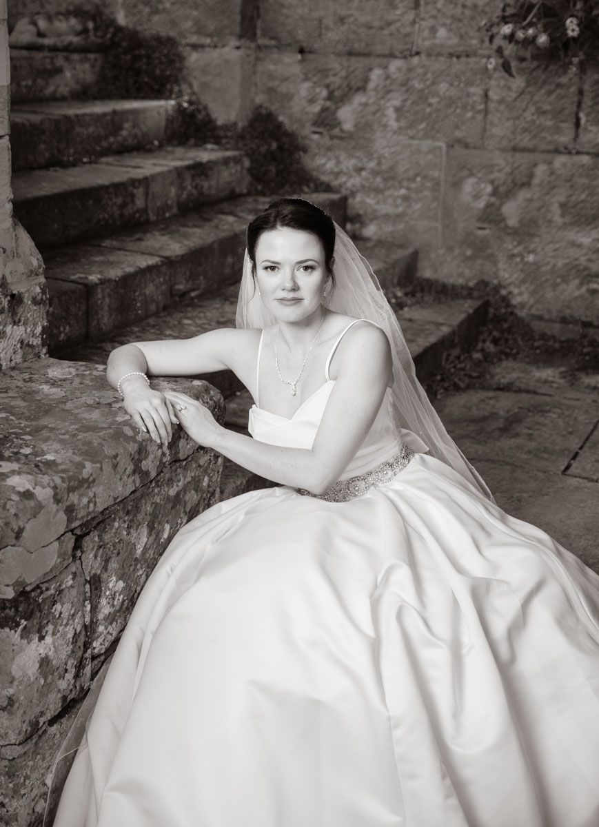 Black and white shot of bride in elegant pose on castle steps | Wadhurst Castle
