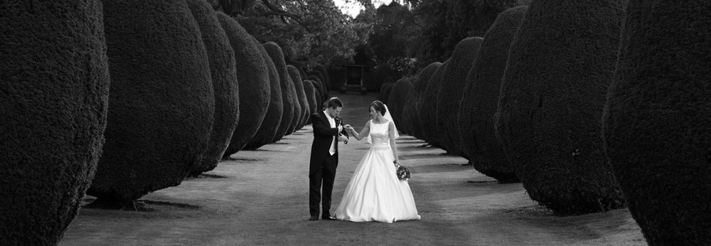 Bride and groom in grand gardens of country mansion, in black and white