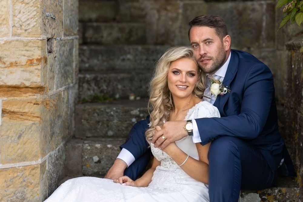 Bride and groom sitting on steps of Wadhurst Castle