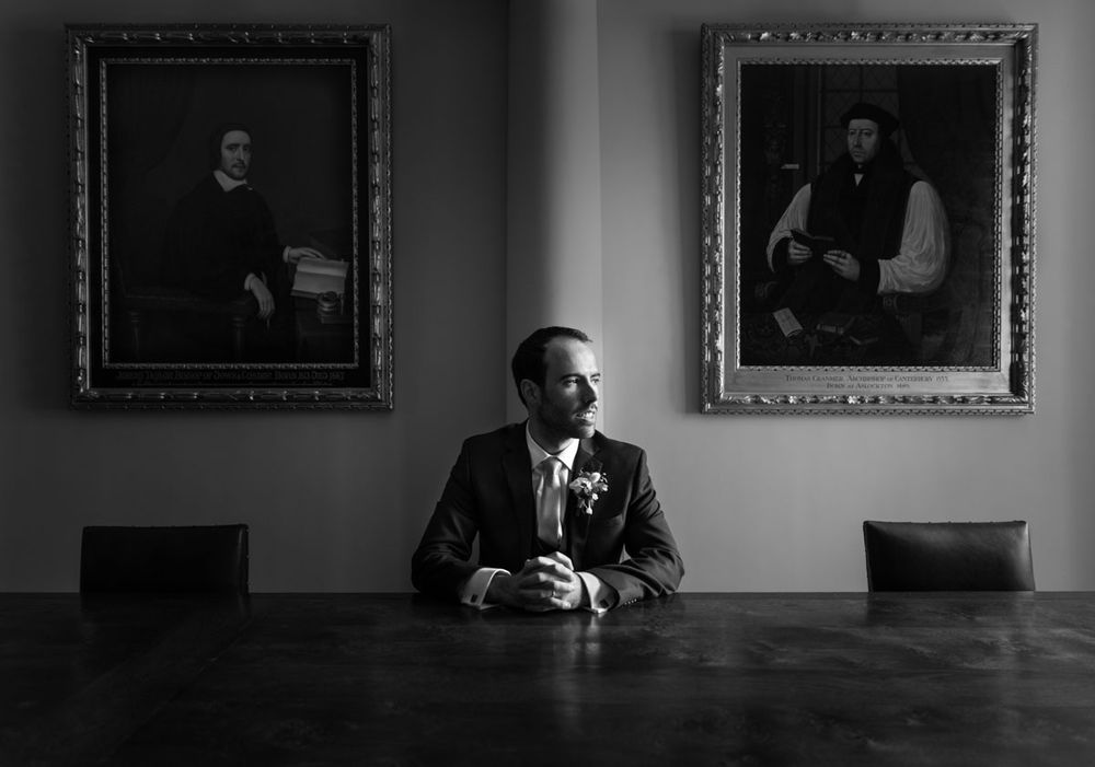 Stylish shot of groom at an antique table in medieval priory