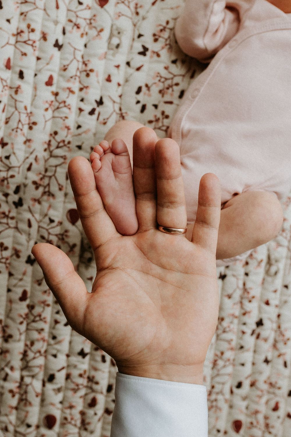 Close-up series of baby hands reaching and grasping against a floral patterned background.