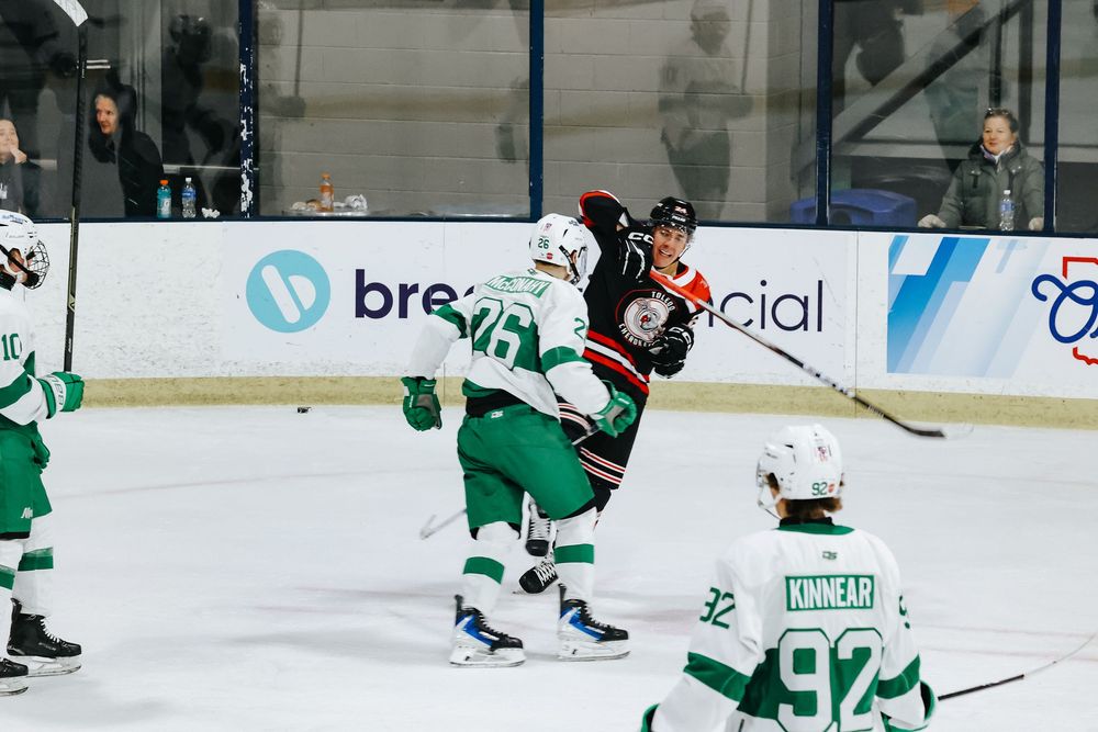Hockey players in green and black jerseys compete for the puck during an intense ice hockey match.