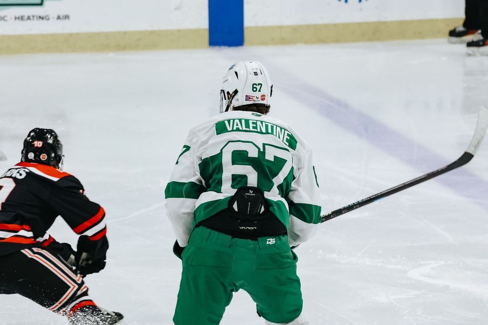 Hockey players in green and black jerseys compete for the puck during an intense ice hockey match.