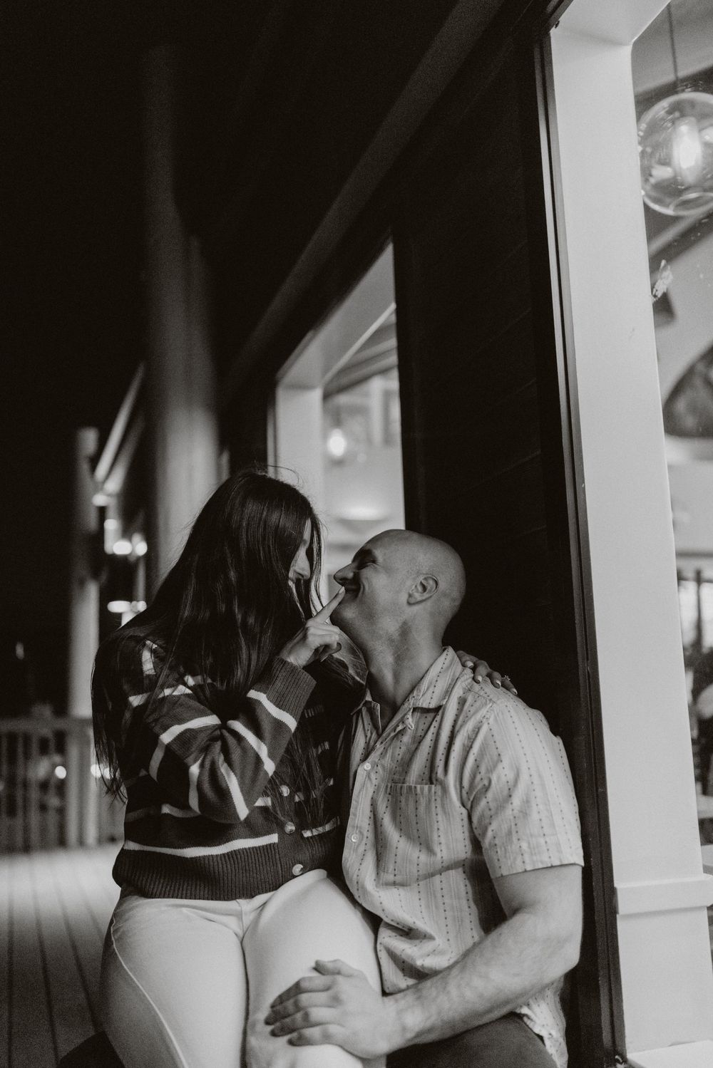 A romantic black and white photo series showing a couple embracing and kissing on a porch at night.
