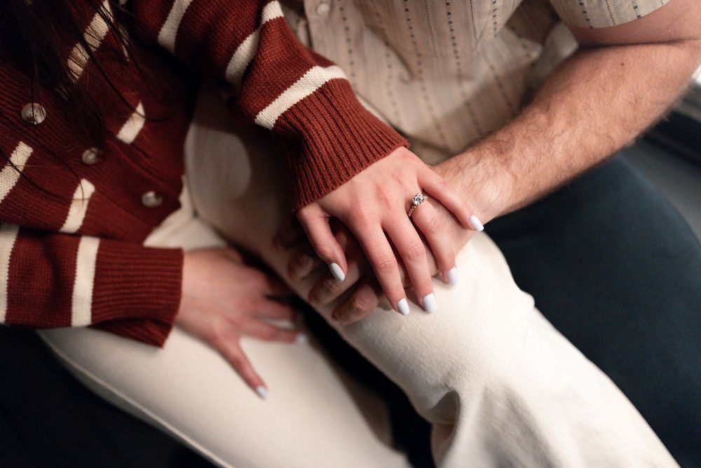 Close-up view of hands resting on legs wearing a burgundy and white striped sweater.