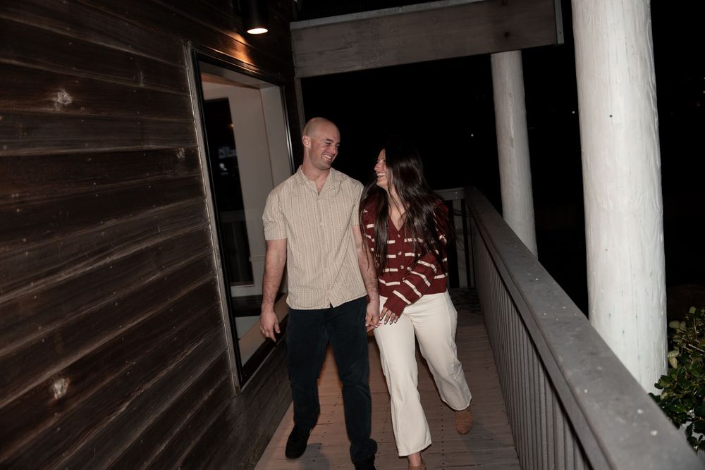 Two people walk down a dark staircase at night while being photographed by paparazzi cameras.