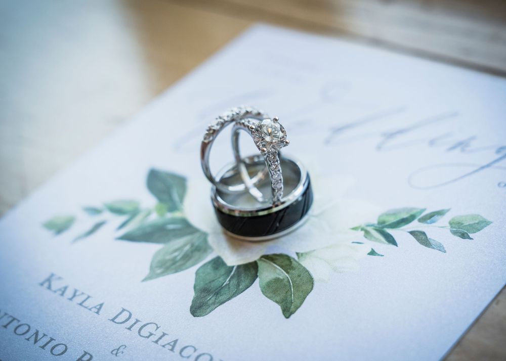 Wedding rings and diamond engagement ring displayed on floral botanical wedding invitation stationery.