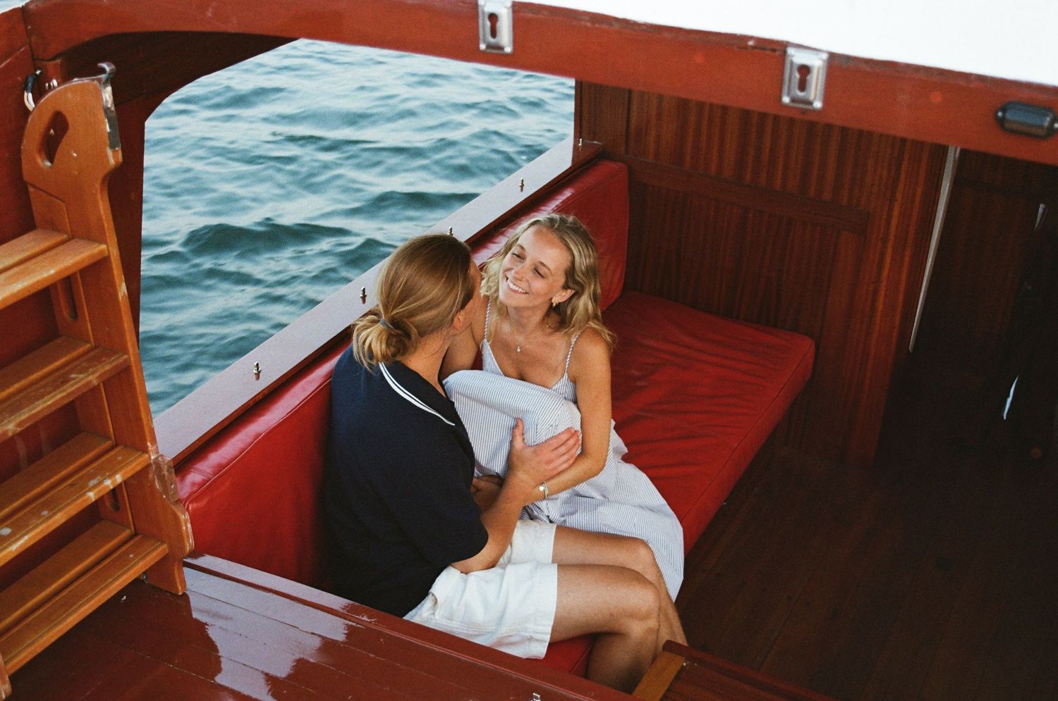 A couple shares a romantic moment inside a vintage red car, seen through the car window in a series of sequential photos.