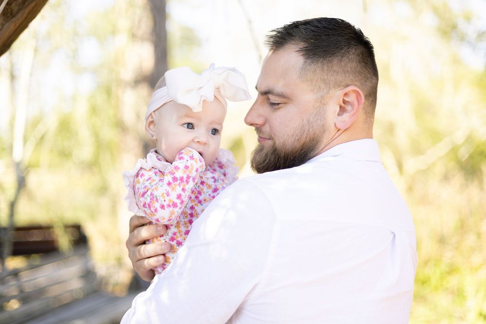 A couple embraces in a tender moment outdoors during a fall photo session with golden sunlight filtering through trees.