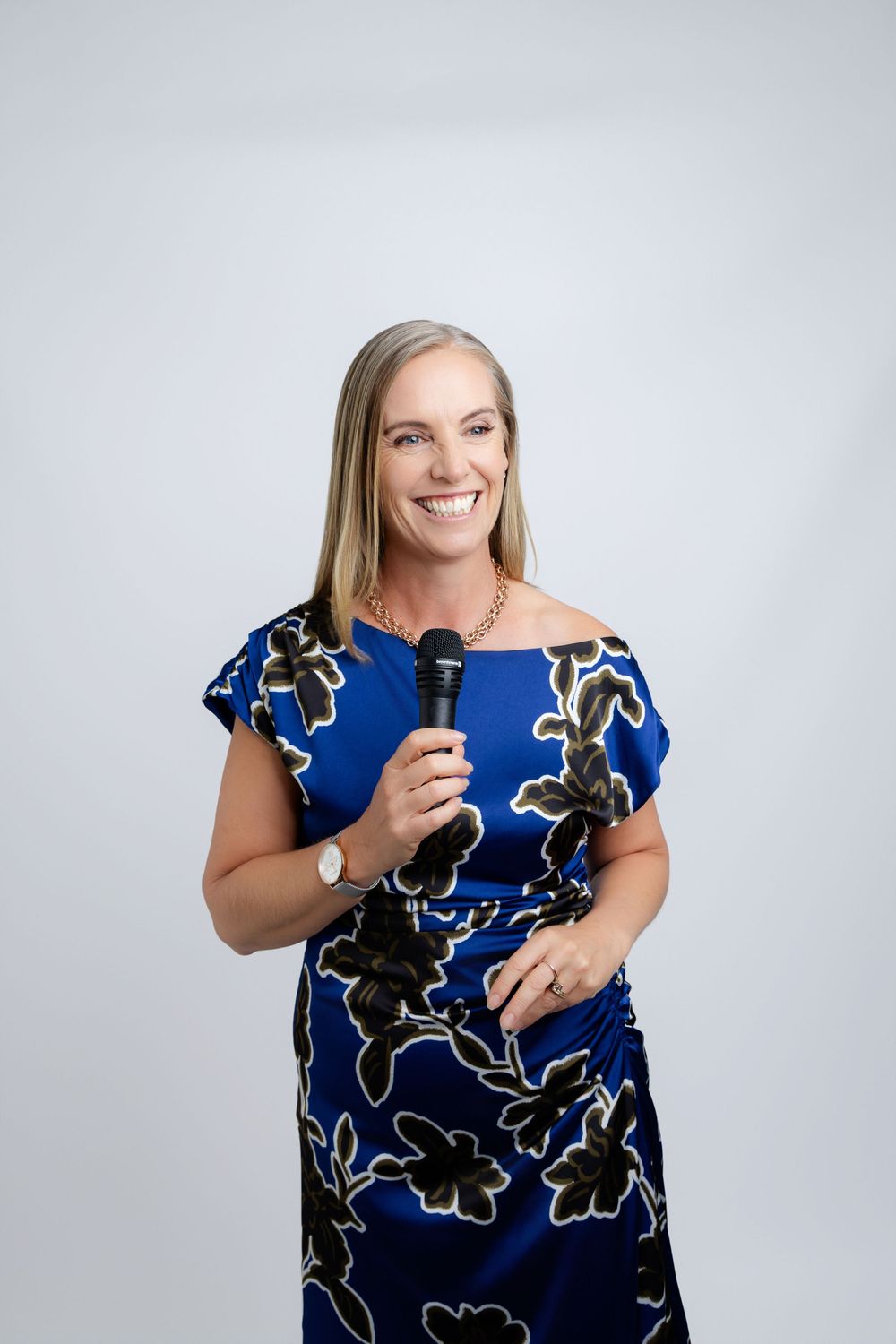 branding photos of a professional speaker wearing a vibrant blue floral dress holding a microphone