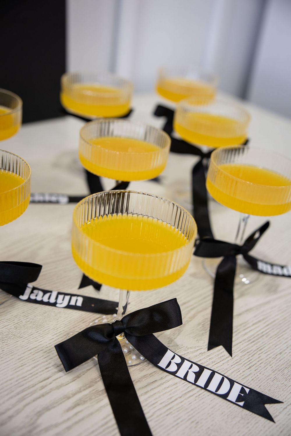 Yellow cocktails decorated with black ribbons and bride tags for wedding celebration.