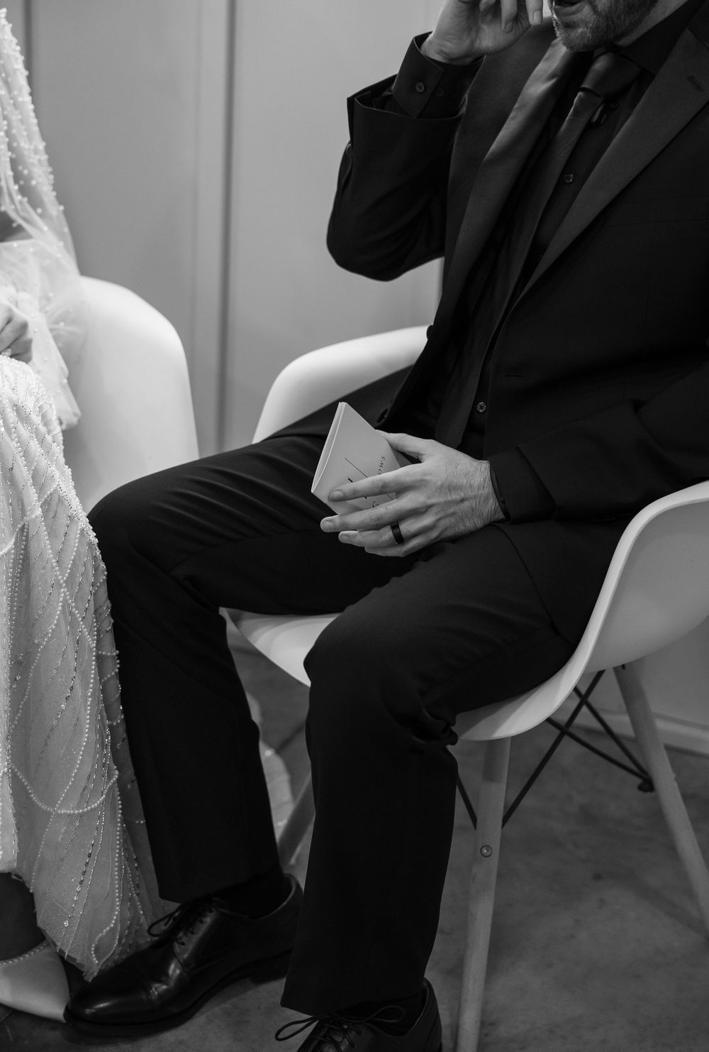 Black and white photo of wedding ceremony guests seated in formal attire.