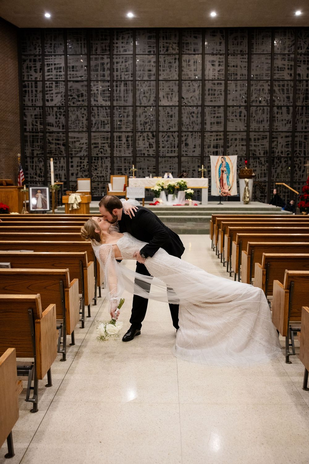 Dramatic church wedding photos showing couple in dip pose across empty pews.