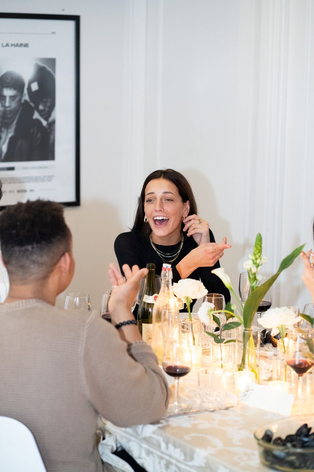 Dinner party guests enjoying conversation around a candlelit table with wine glasses.
