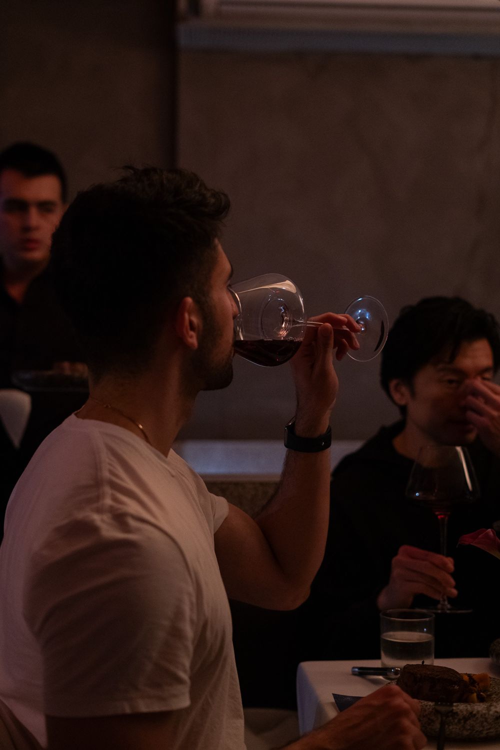 Guest enjoying wine at a dimly lit dinner gathering.