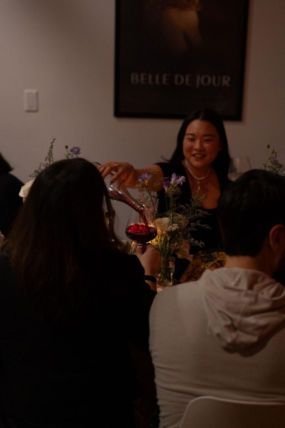 A dinner gathering with wine service under a vintage French film poster.