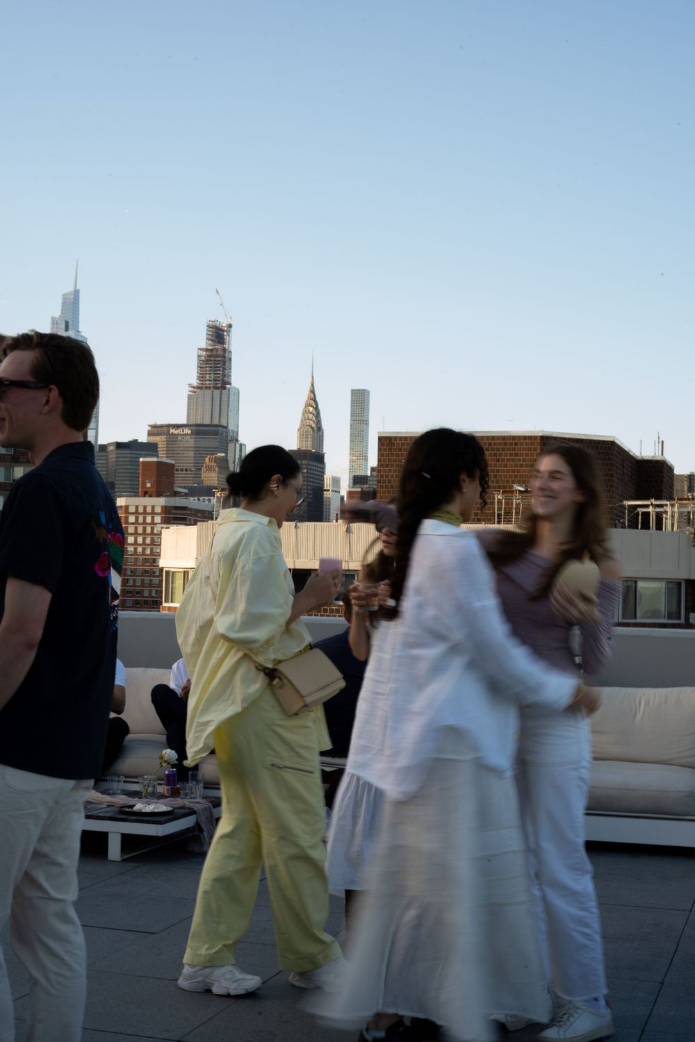 Group mingling on a rooftop terrace with New York City buildings visible in the background.