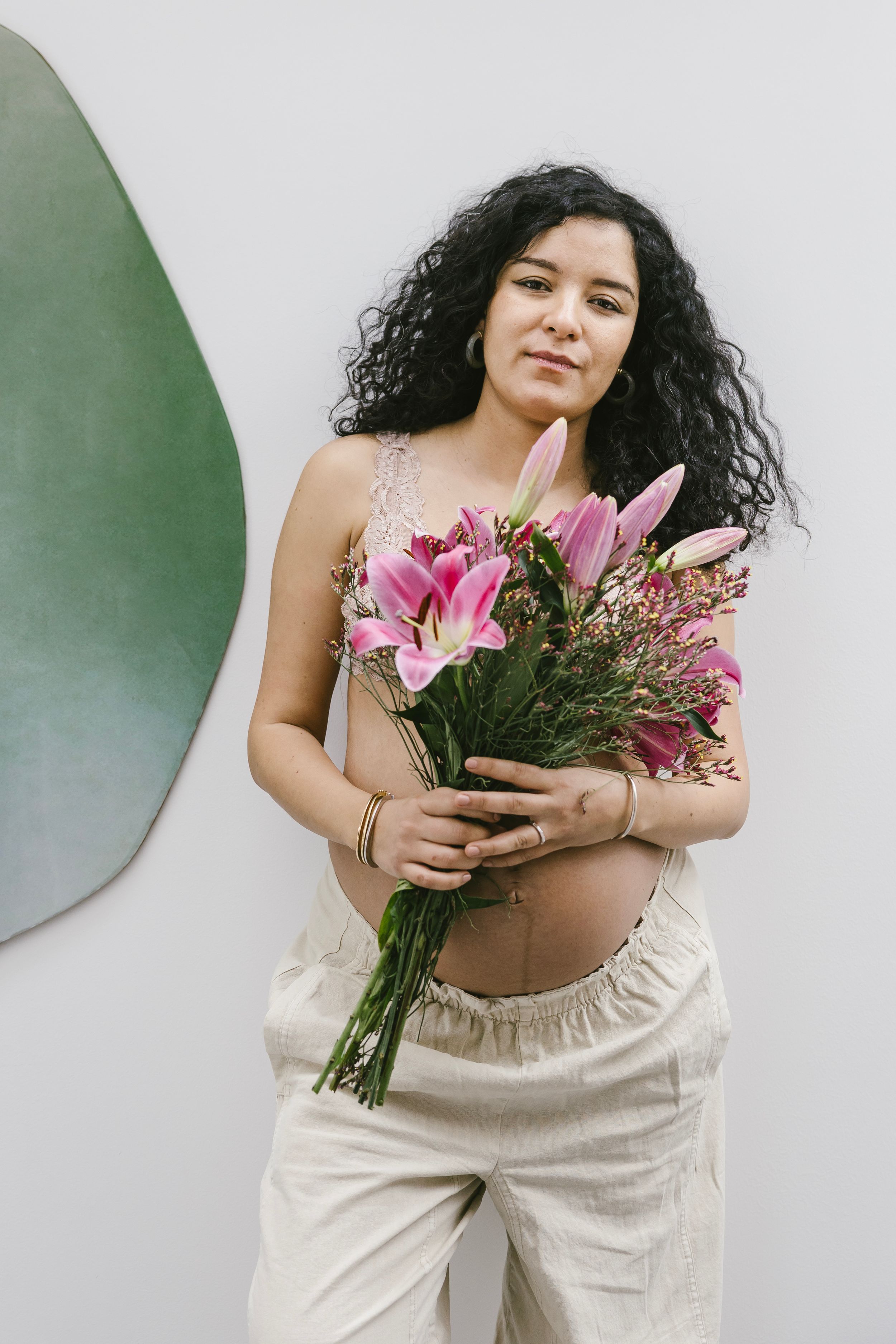 A series of artistic photos showing someone in cream-colored clothing holding a vibrant bouquet of pink lilies and flowers.