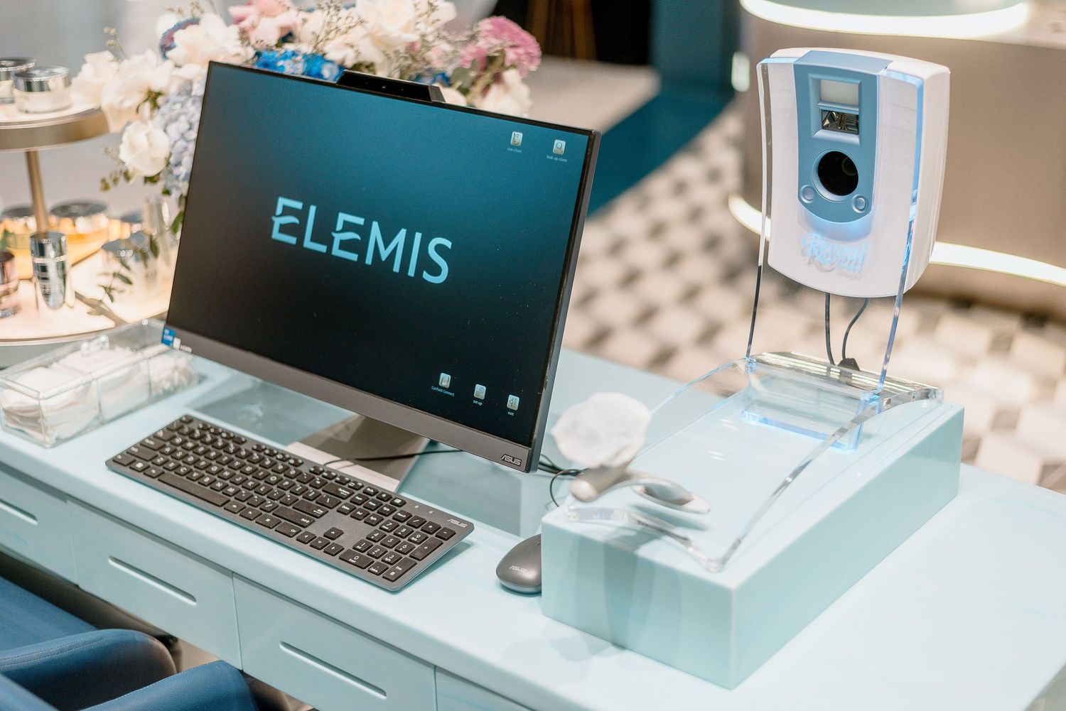 Elemis brand displayed on laptop screen with beauty device setup on modern white desk display.