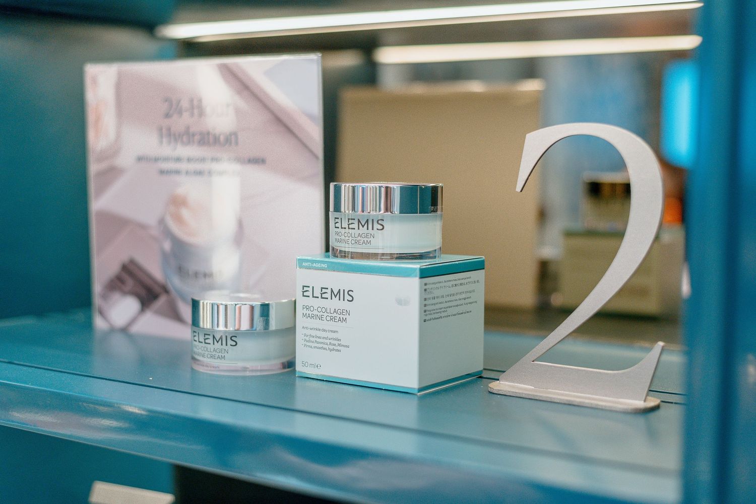 Elemis skincare products and packaging displayed on blue-tinted retail shelf.