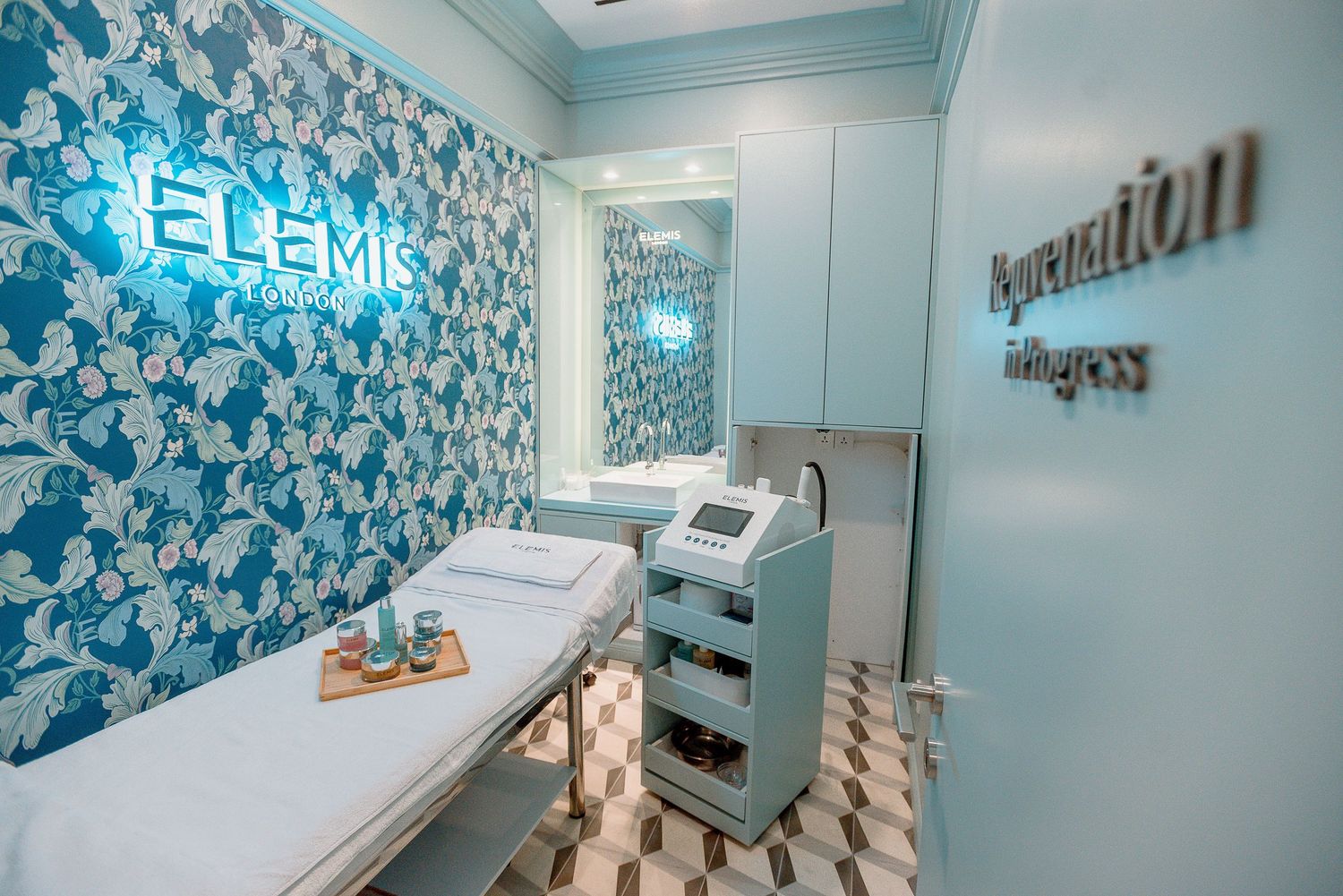 Modern medical treatment room with blue floral wallpaper and white equipment in a spa or clinic setting.