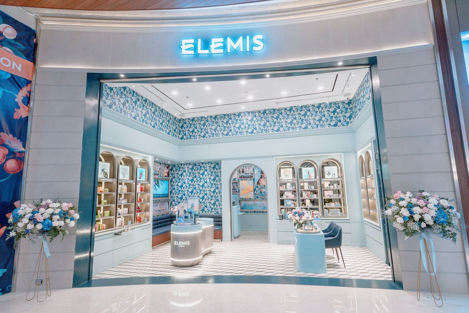 Modern Elemis luxury spa and skincare store entrance with blue and white decor and illuminated signage in an upscale mall.
