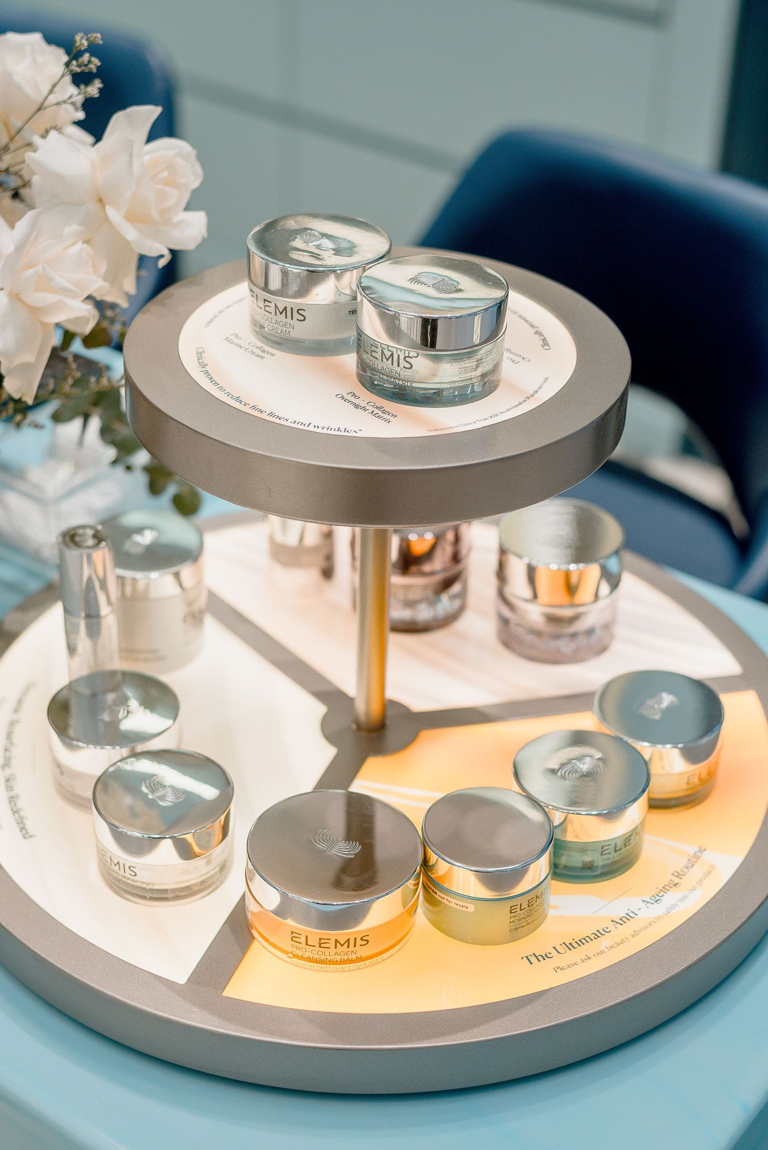 Elegant two-tiered display stand showcasing luxury skincare products with white flowers and candle accessories.