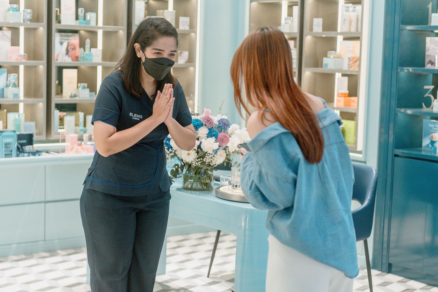 Healthcare worker in black scrubs and mask performs a nasal swab test on a patient wearing blue in a medical office.