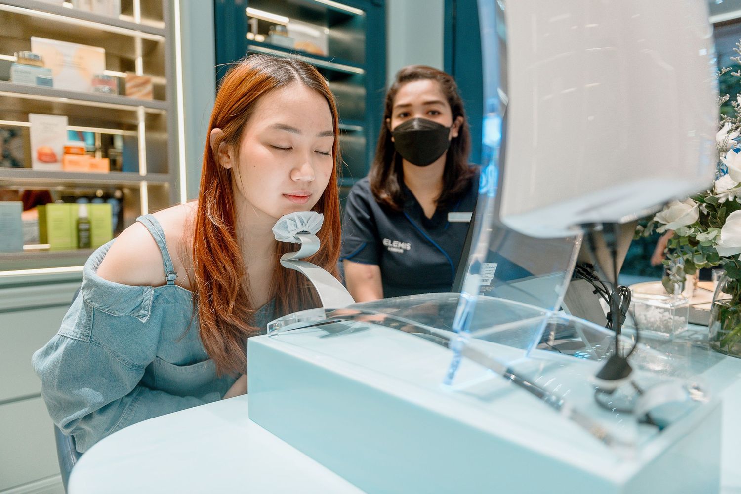 Two people looking at a display screen in a modern retail environment with clean white decor and shelving.