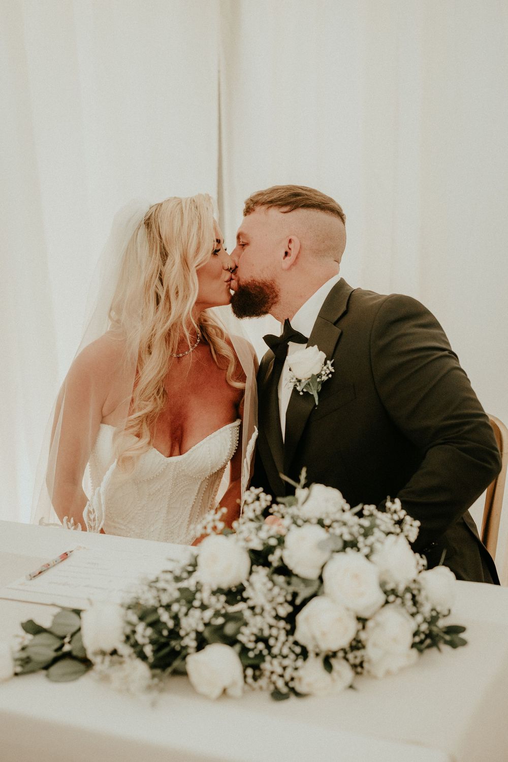 A romantic wedding moment captured with white roses and baby's breath floral arrangement in the foreground.