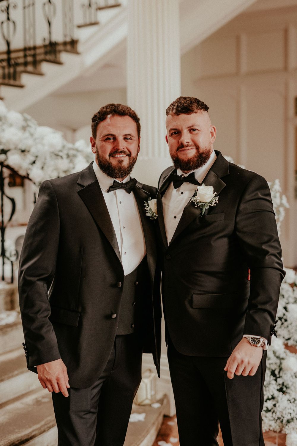 Two men in black tuxedos share joyful moments at a formal wedding celebration. Cornwall wedding photography scorrier house