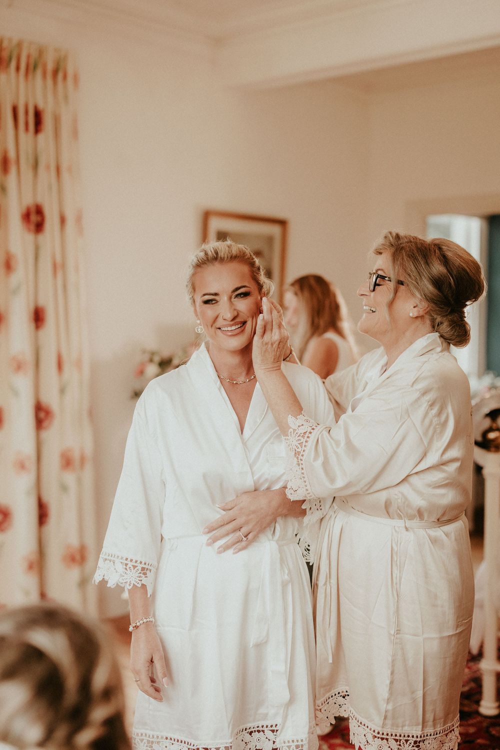 A group wearing matching white robes with lace trim prepare for a wedding celebration. Cornwall wedding photography scorrier house