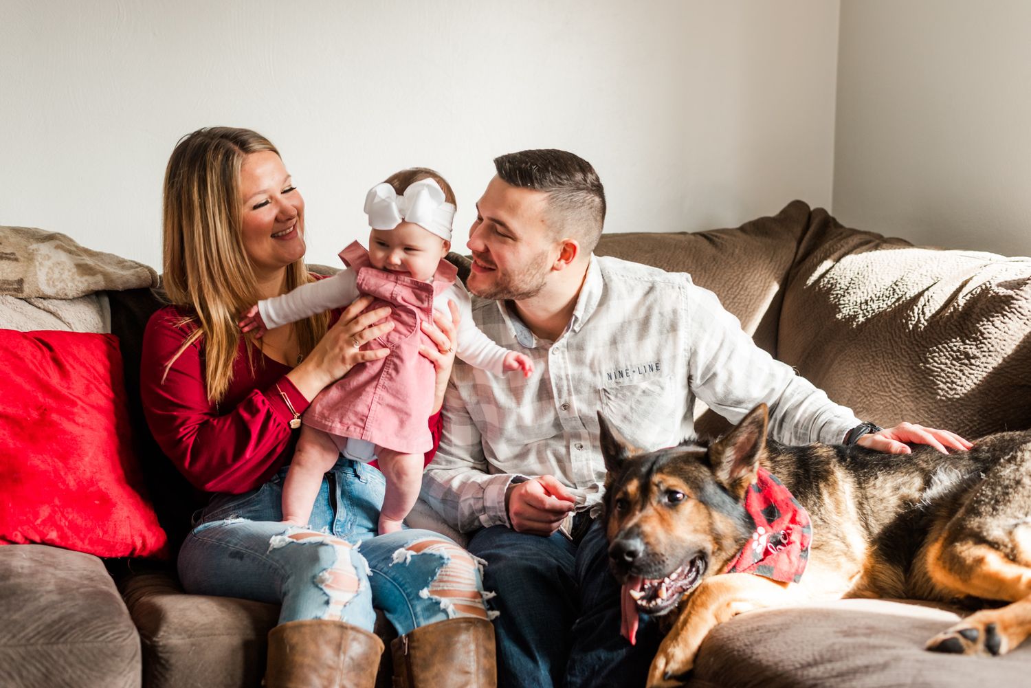 Family sitting on couch in living room with natural light for lifestyle candid family photos at home
