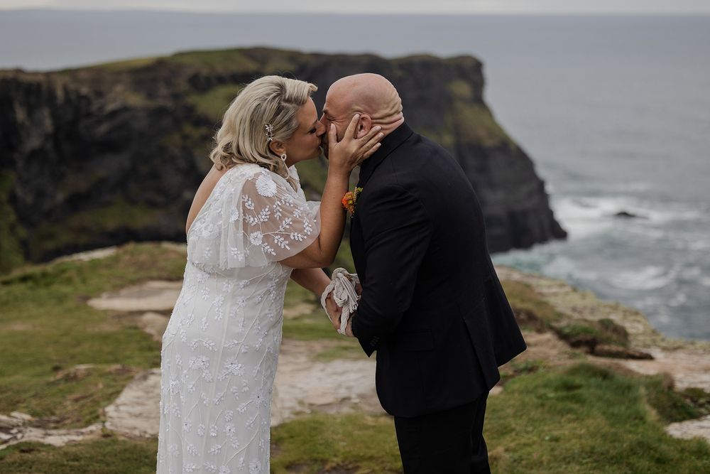 Adventurous US couple eloping and kissing in Ireland’s rugged scenery.
