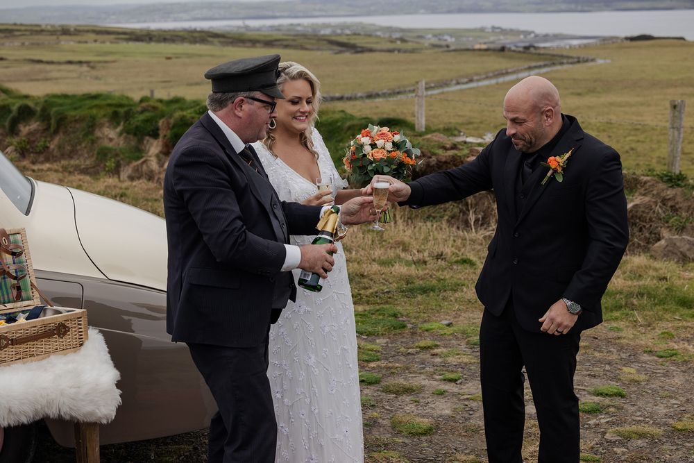 Couple toasting at dramatic Irish coastline during elopement.