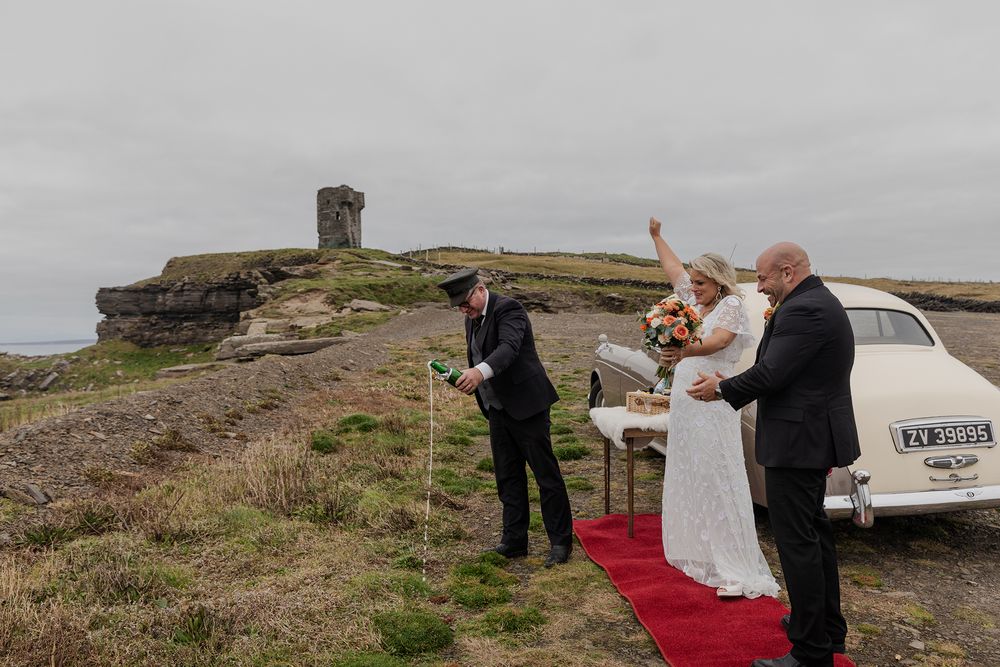 Couple toasting at dramatic Irish coastline during elopement.